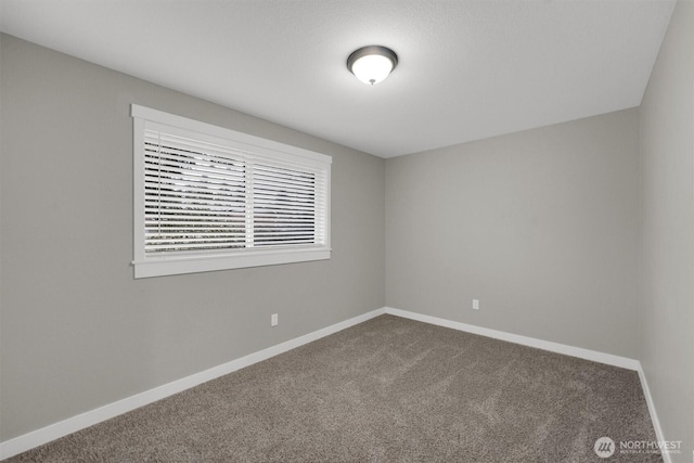 carpeted empty room featuring baseboards