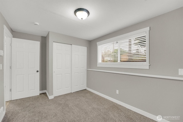 unfurnished bedroom with a closet, baseboards, and carpet