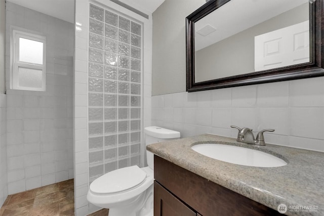 full bath with toilet, vanity, tile walls, and walk in shower