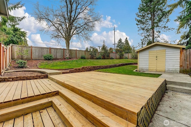 wooden terrace with an outdoor structure, a fenced backyard, a storage unit, and a yard