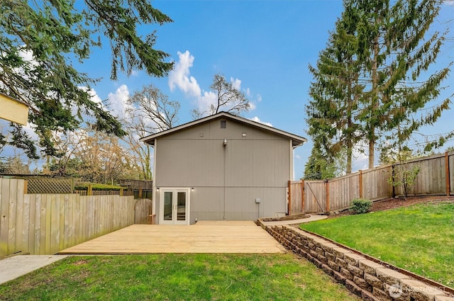 back of property with french doors, a fenced backyard, a lawn, and a wooden deck