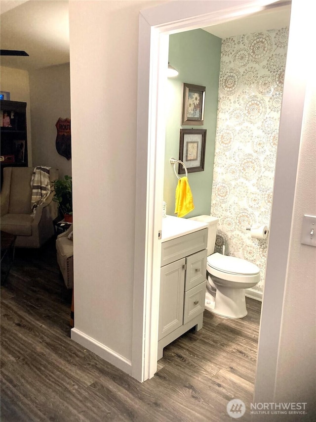 half bathroom with toilet, wood finished floors, and vanity