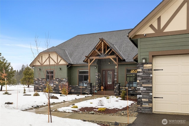 english style home featuring a garage, stone siding, and a shingled roof