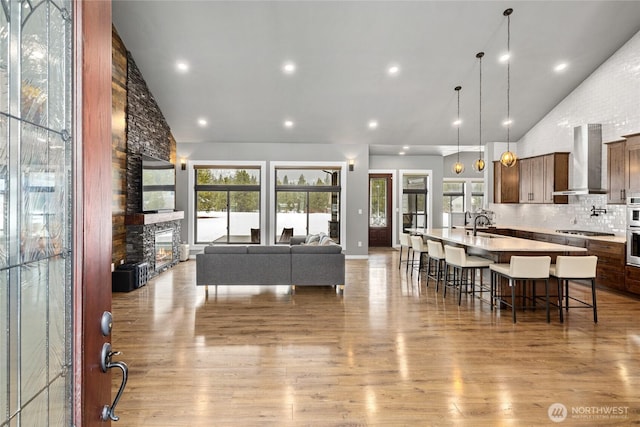 living area featuring high vaulted ceiling, a fireplace, wood finished floors, and recessed lighting