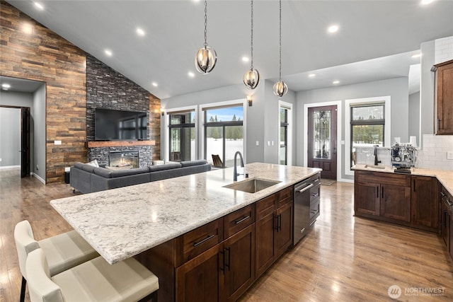 kitchen with light wood-style floors, a healthy amount of sunlight, a sink, and a stone fireplace