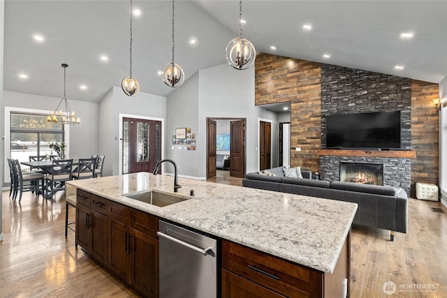 kitchen featuring dishwasher, light wood finished floors, a fireplace, and a sink