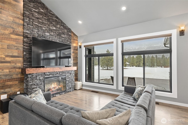 living room with high vaulted ceiling, a fireplace, wood finished floors, visible vents, and baseboards