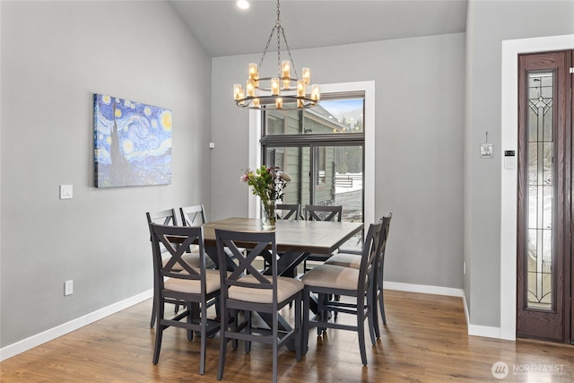 dining space with baseboards, a chandelier, and wood finished floors