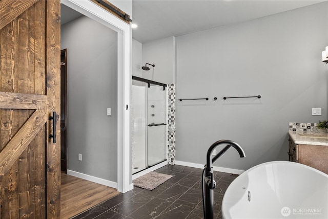 bathroom with marble finish floor, a freestanding bath, a stall shower, vanity, and baseboards