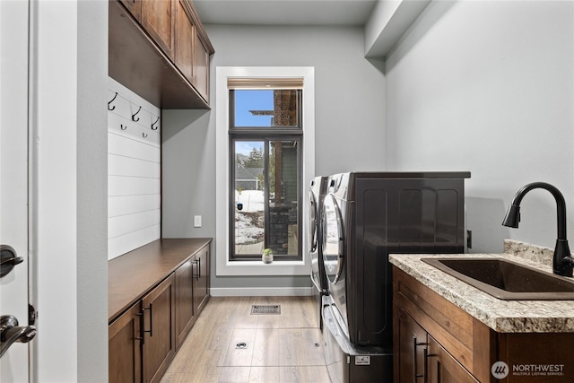 washroom featuring cabinet space, light wood finished floors, visible vents, independent washer and dryer, and a sink