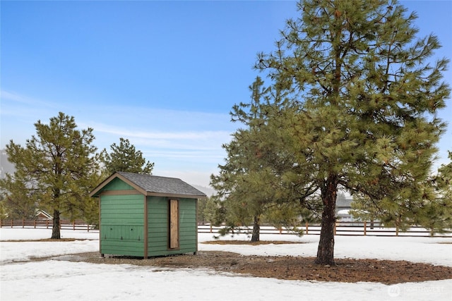 yard covered in snow featuring an outbuilding, a storage unit, and fence