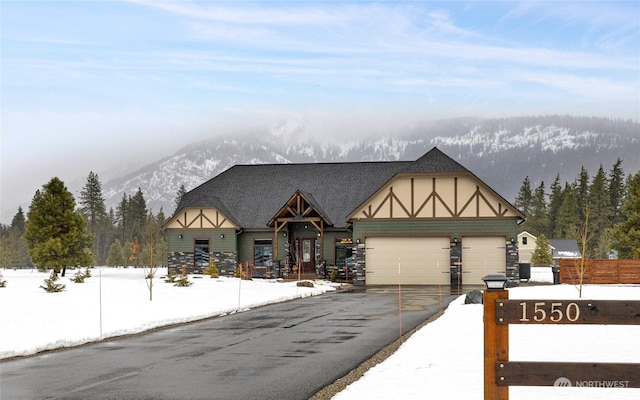 tudor-style house featuring a garage, driveway, fence, and a mountain view