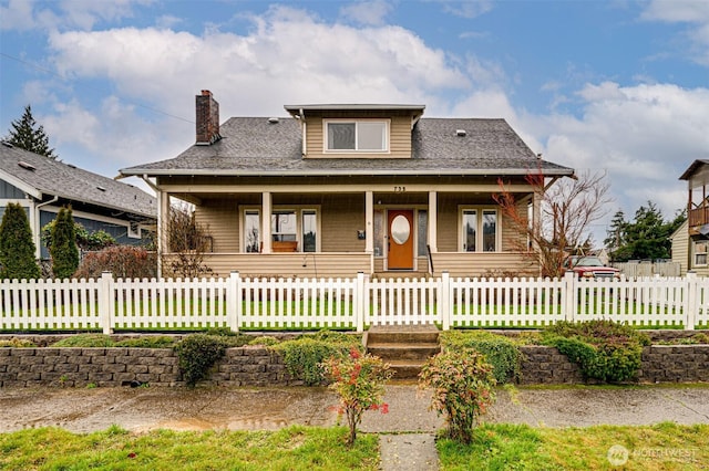 bungalow-style house featuring covered porch, a fenced front yard, and a chimney