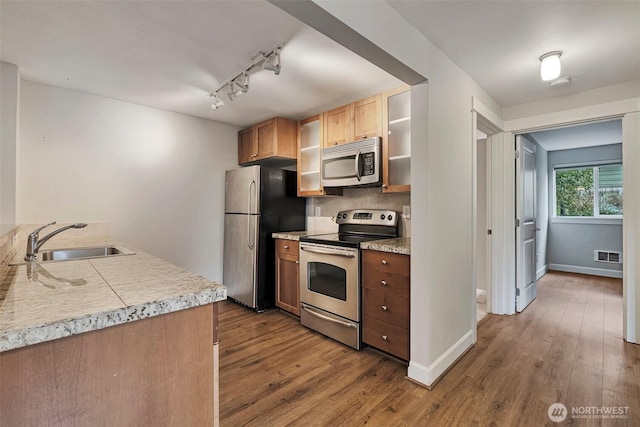 kitchen with wood finished floors, light countertops, appliances with stainless steel finishes, and a sink