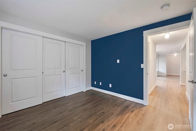 unfurnished bedroom featuring a closet, baseboards, and wood finished floors