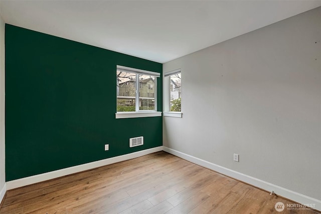 empty room featuring visible vents, baseboards, and wood finished floors