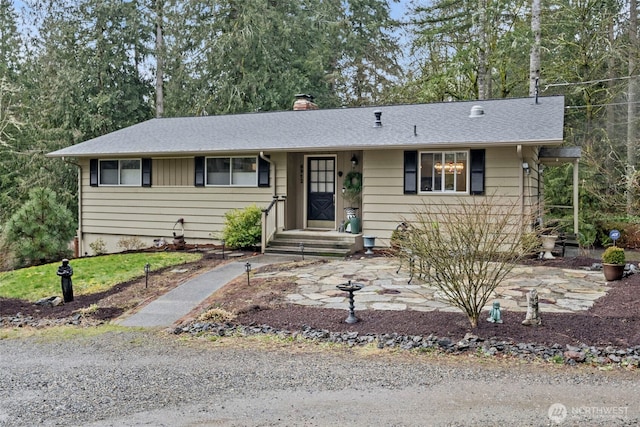 ranch-style home with roof with shingles and a chimney