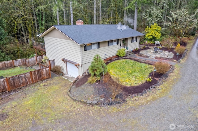 ranch-style home featuring an attached garage, fence, roof with shingles, a front lawn, and a chimney