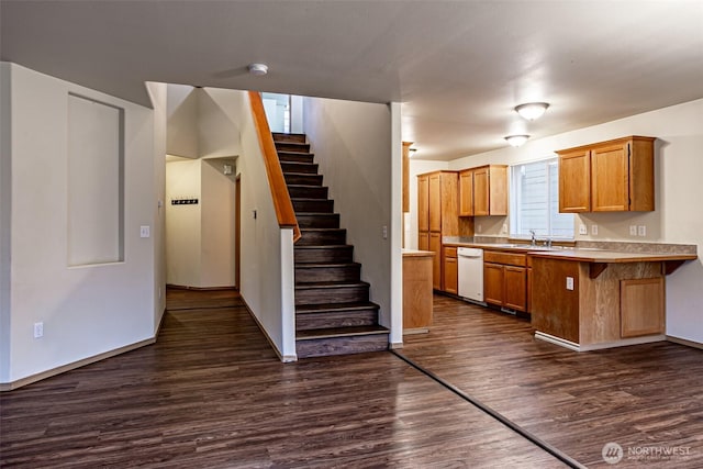 kitchen featuring dark wood finished floors, dishwasher, brown cabinets, light countertops, and a sink