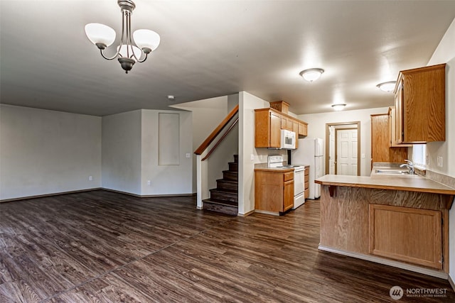 kitchen featuring white appliances, dark wood-style floors, a peninsula, light countertops, and a sink