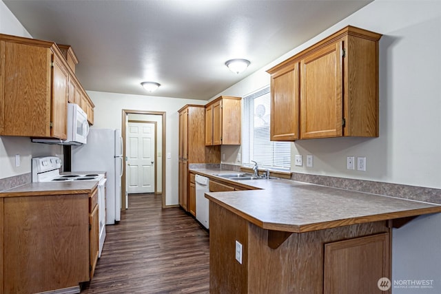 kitchen with white appliances, brown cabinets, a sink, and a peninsula