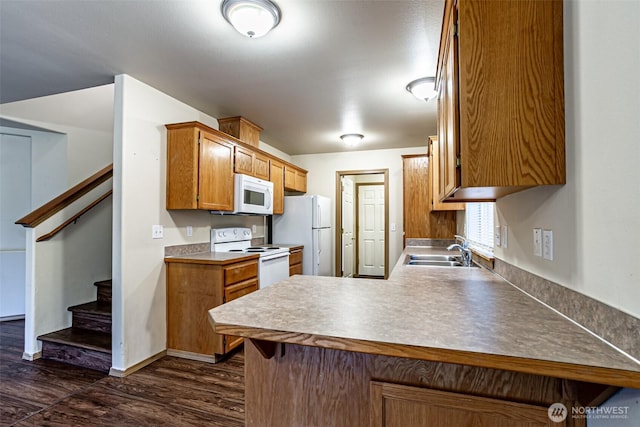 kitchen with a peninsula, white appliances, a sink, light countertops, and brown cabinets