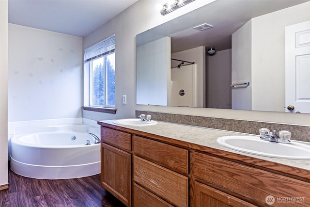 bathroom with double vanity, wood finished floors, a sink, and a bath