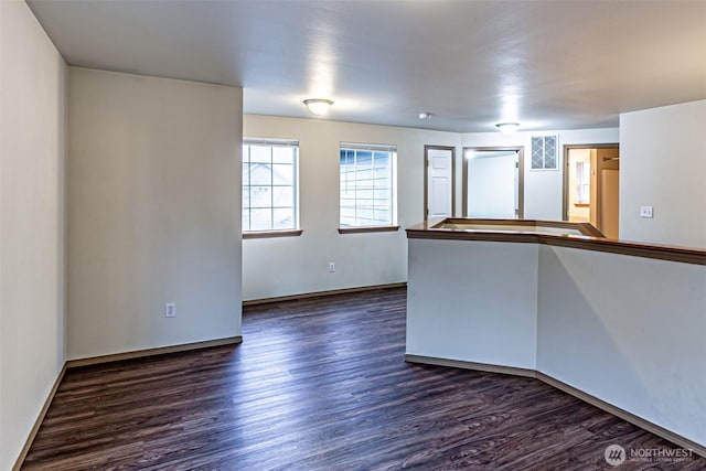 empty room with dark wood-style floors and baseboards