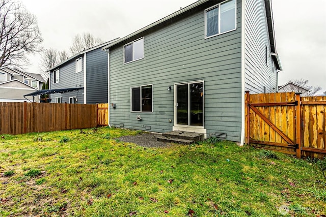 back of house with entry steps, crawl space, a lawn, and a fenced backyard