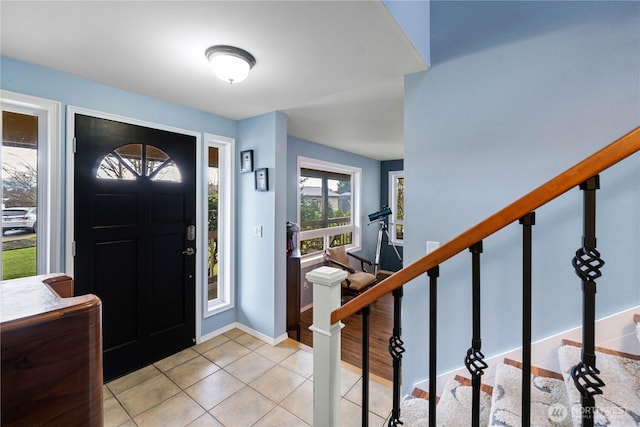 entryway featuring stairs, baseboards, and light tile patterned floors