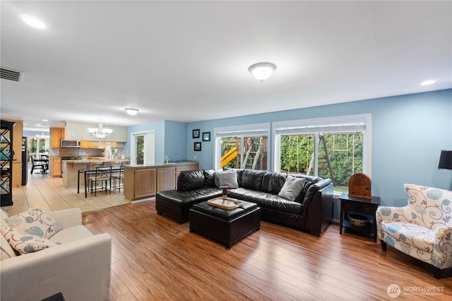 living room with light wood finished floors, recessed lighting, visible vents, and an inviting chandelier