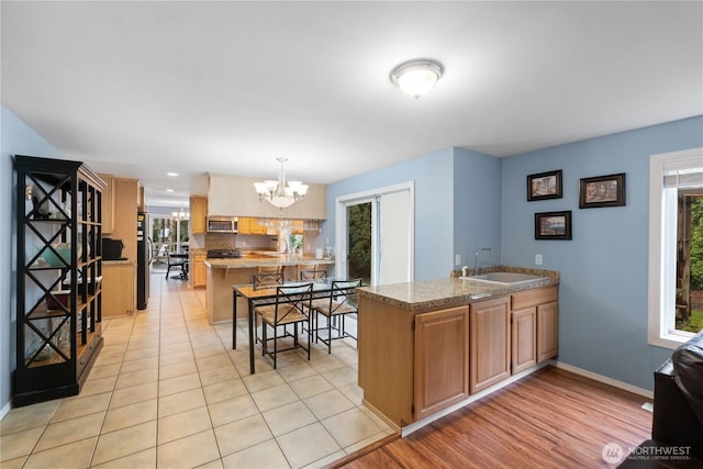 kitchen featuring a peninsula, plenty of natural light, a sink, and pendant lighting