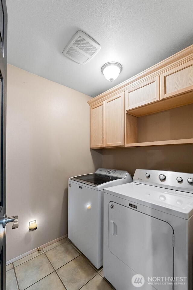 laundry area featuring light tile patterned floors, cabinet space, visible vents, separate washer and dryer, and baseboards