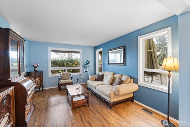 living area featuring dark wood-style flooring, visible vents, and baseboards