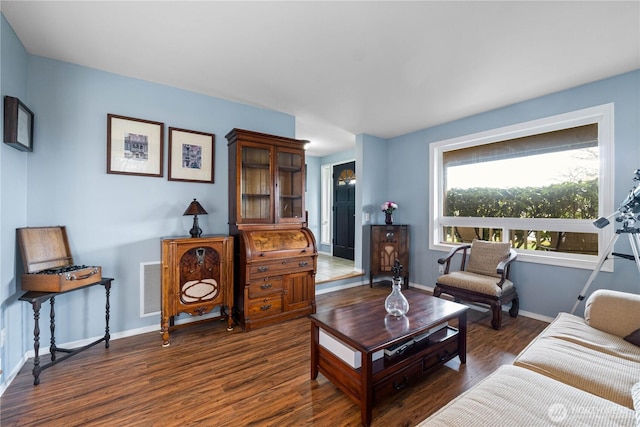 living room with dark wood-style flooring, visible vents, and baseboards