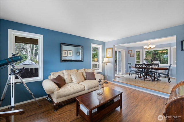 living room featuring a chandelier, baseboards, wood finished floors, and a healthy amount of sunlight