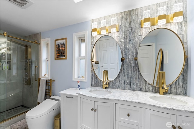 bathroom featuring toilet, a sink, visible vents, a shower stall, and double vanity