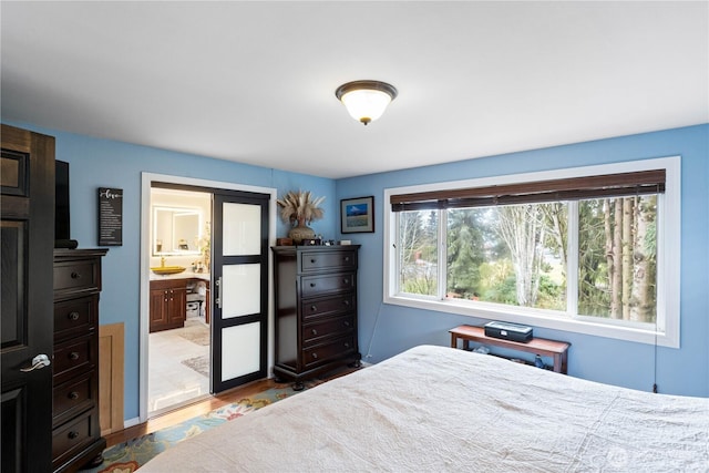 bedroom with ensuite bathroom and light wood-style flooring