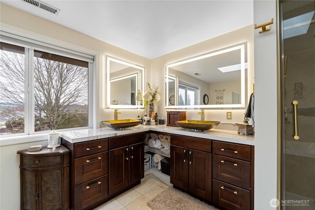 full bathroom featuring double vanity, visible vents, a sink, and tile patterned floors