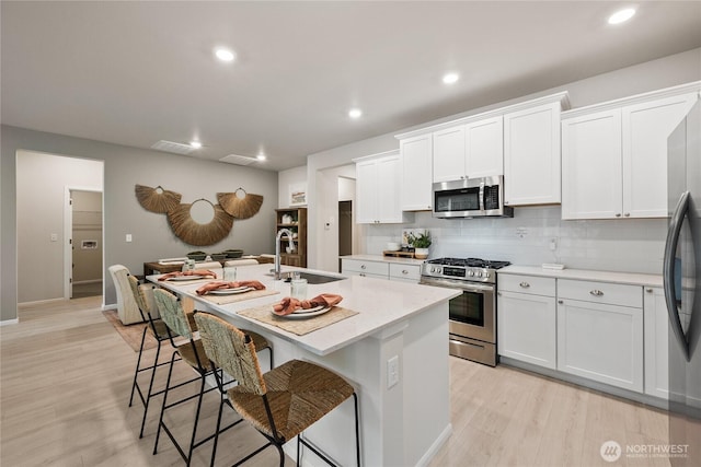 kitchen featuring white cabinetry, a center island with sink, appliances with stainless steel finishes, and a sink