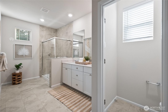 full bathroom with a stall shower, vanity, visible vents, and baseboards