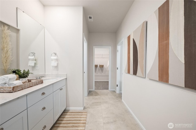 bathroom featuring a spacious closet, vanity, and baseboards