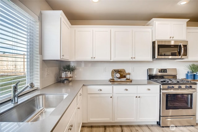 kitchen with recessed lighting, light countertops, appliances with stainless steel finishes, white cabinetry, and a sink