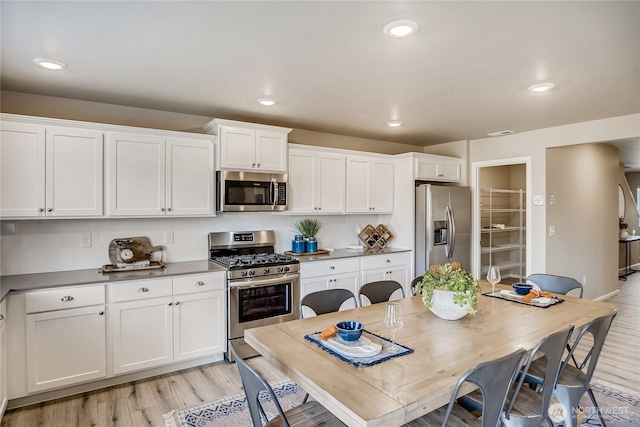 kitchen featuring stainless steel appliances, white cabinetry, and light wood-style floors