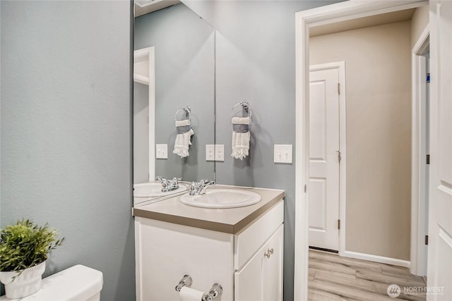 bathroom with toilet, wood finished floors, and vanity