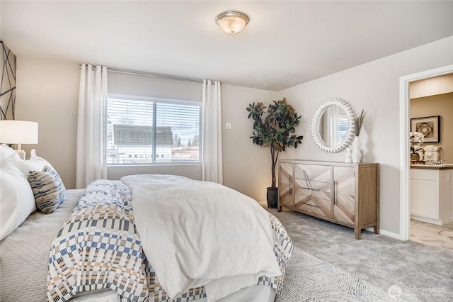 bedroom featuring ensuite bathroom, baseboards, and light colored carpet