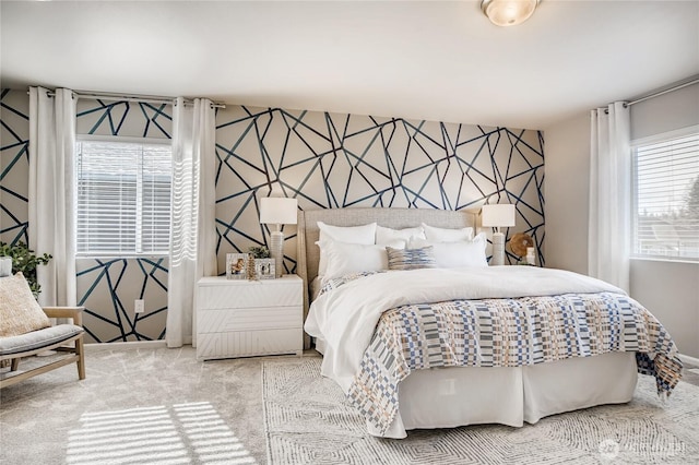 bedroom featuring an accent wall, multiple windows, carpet flooring, and wallpapered walls