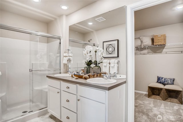 full bath with a spacious closet, double vanity, a sink, and a shower stall