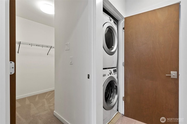 laundry area featuring laundry area, baseboards, stacked washer / drying machine, and carpet flooring