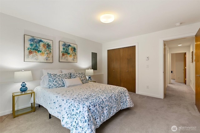 bedroom with baseboards, a closet, and light colored carpet